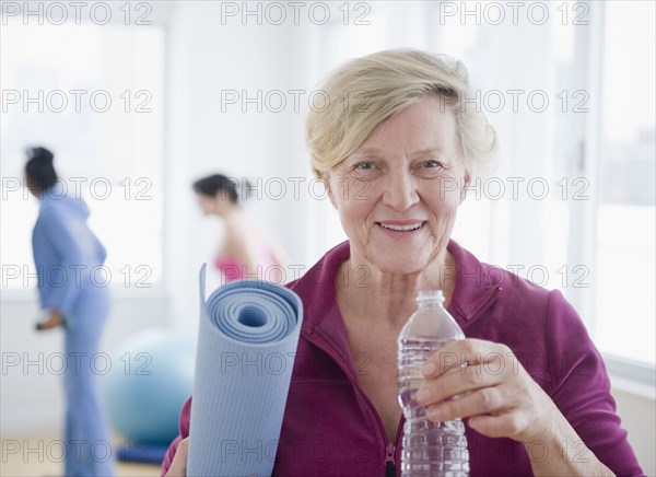 Caucasian woman with yoga mat drinking water