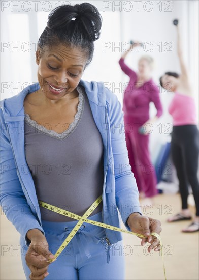 Mixed race woman measuring her waist