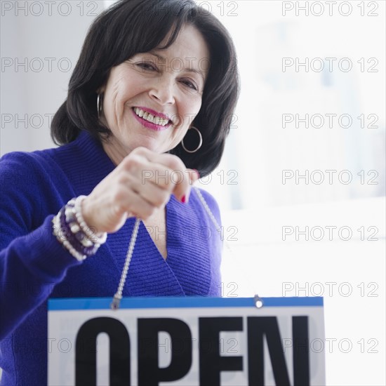 Mixed race woman hanging open sign