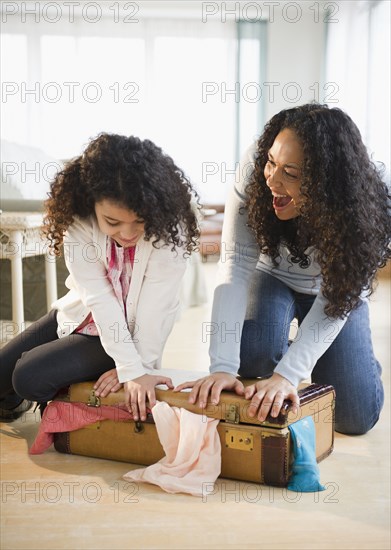 Mother and daughter shutting suitcase