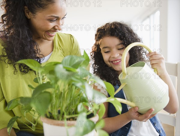 Mother and daughter watering plant together