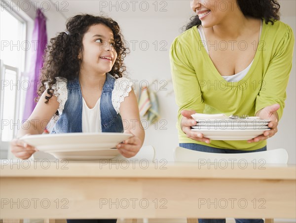 Mother and daughter setting the table