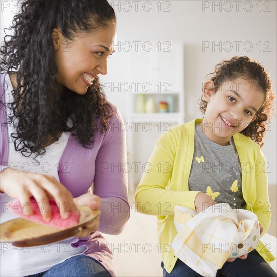 Mother and daughter drying dishes together