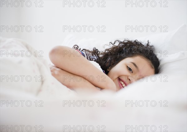 Smiling Hispanic girl laying in bed