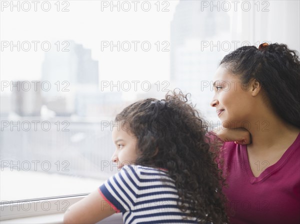 Mother and daughter looking out window