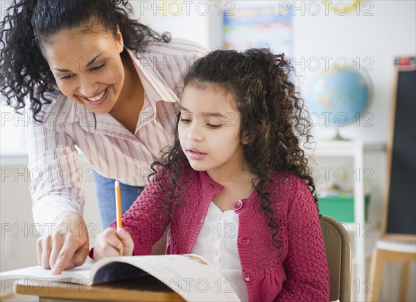 Teacher helping girl with school work in classroom
