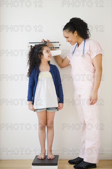 Nurse weighing girl on scales