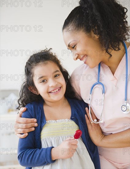 Smiling nurse giving girl lollipop