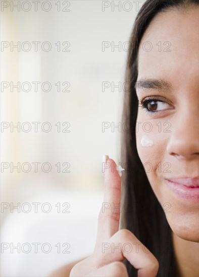 Hispanic teenager applying moisturizer