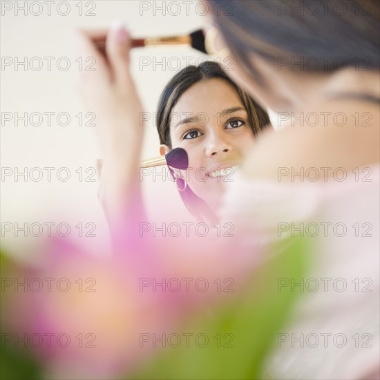 Hispanic teenager putting on blush