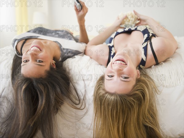 Teenage girls laying on bed upside-down