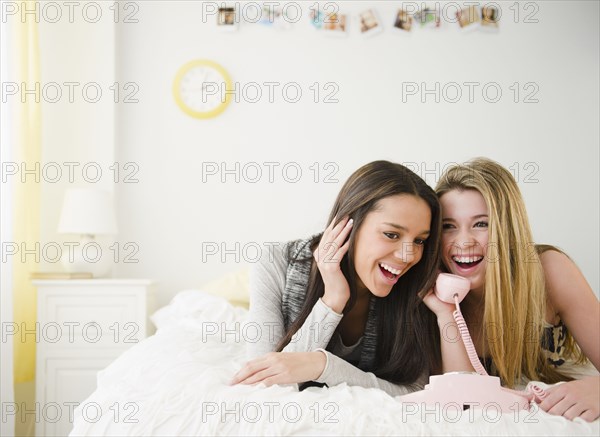 Teenage girls talking on telephone together