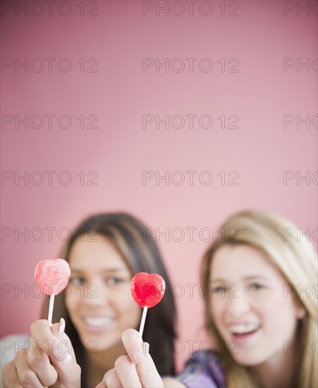 Teenage girls holding heart-shape lollipops