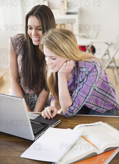 Teenage girls looking at laptop together