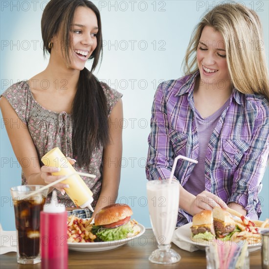 Teenage girls eating hamburgers and french fries