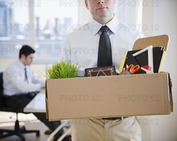 Fired Caucasian businessman carrying personal belongings