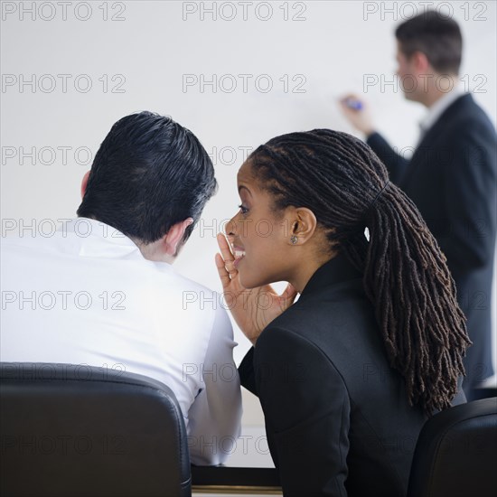 Businesswoman whispering to co-worker in meeting