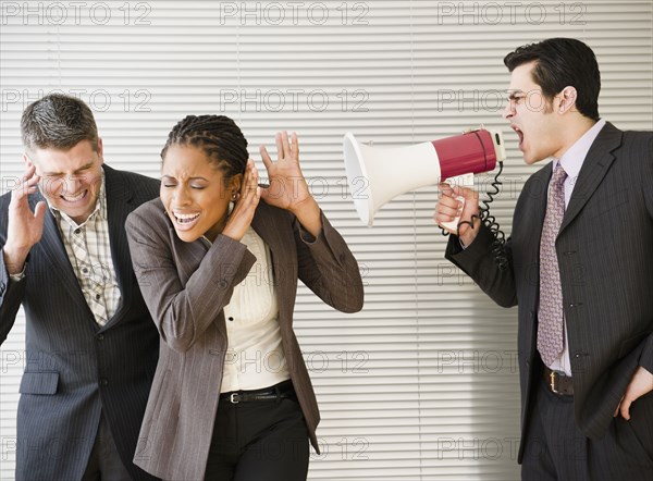 Businessman shouting through bullhorn at co-workers