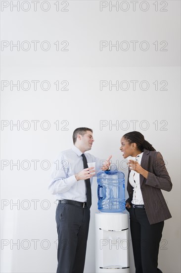 Business people talking together at water cooler