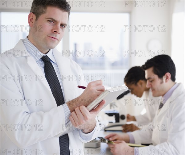 Scientist writing on clipboard in laboratory