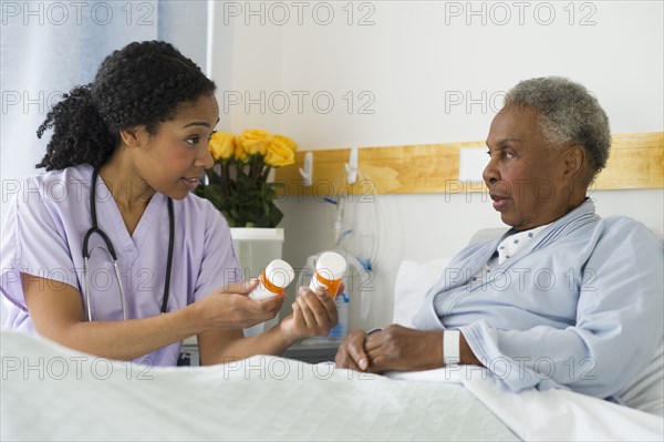 Nurse explaining medication to patient in hospital bed