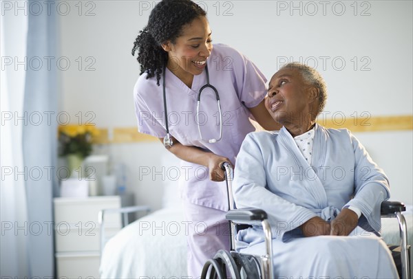 Nurse pushing woman sitting in wheelchair in hospital