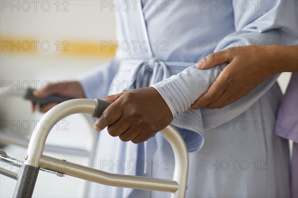 Nurse helping woman use walker in hospital hallway