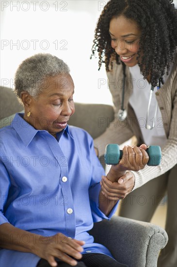 Nurse helping woman exercise with dumbbells