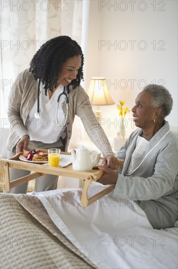 Nurse serving woman breakfast in bed