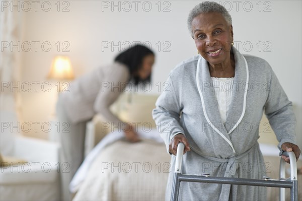 Black woman walking with walker in bedroom