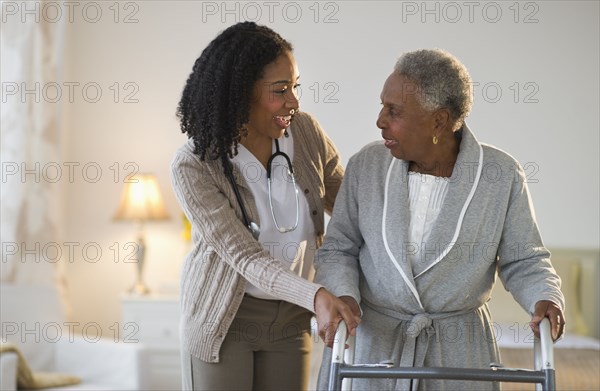 Nurse helping woman walk with walker