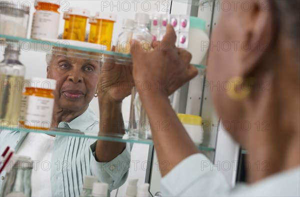 Black woman taking medication from cabinet