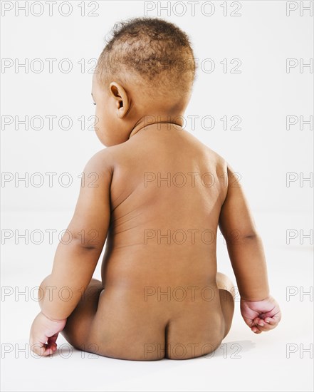 Nude Black baby sitting on floor