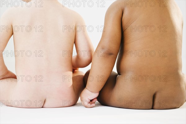 Nude babies sitting on floor