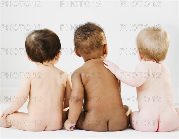 Nude babies sitting on floor