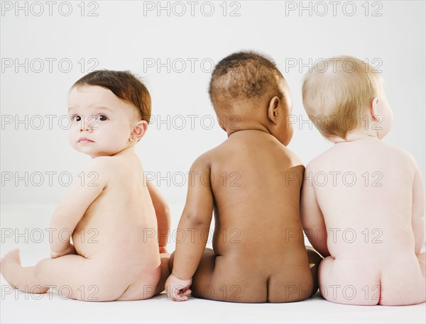 Nude babies sitting on floor
