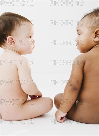 Nude babies sitting on floor