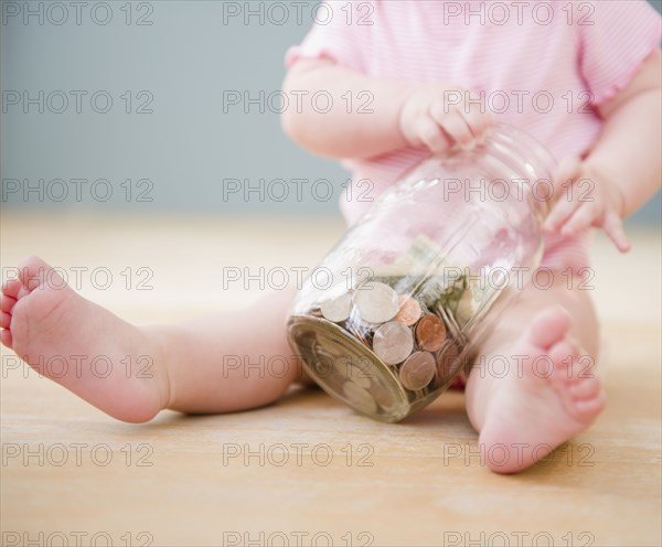 Caucasian baby playing with jar of coins