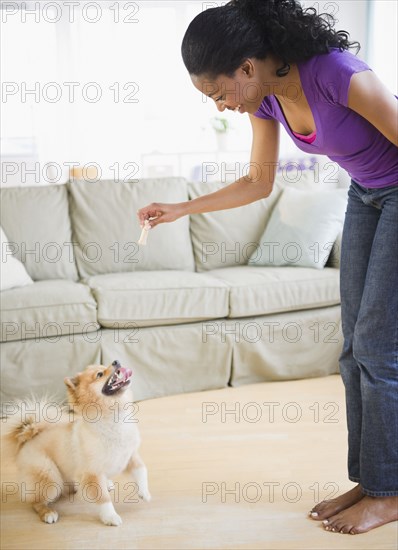 Mixed race woman playing with Pomeranian dog