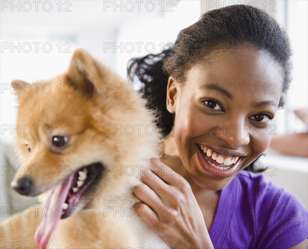 Mixed race woman petting Pomeranian dog