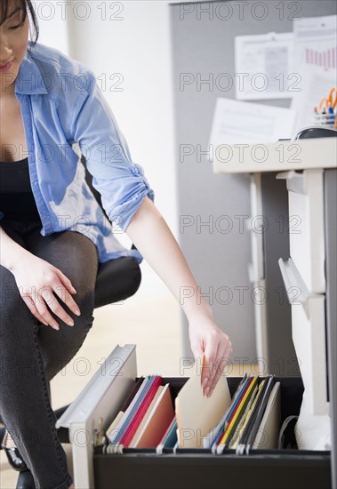 Korean woman removing folder from desk drawer