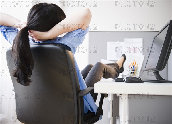 Korean woman sitting at desk with feet up