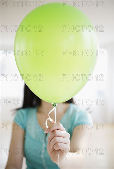 Korean woman holding balloon in front of her face