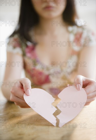 Korean woman holding torn paper heart