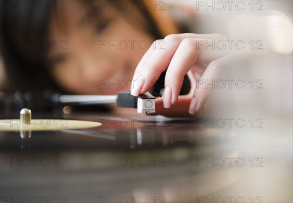 Korean woman putting playing arm on record