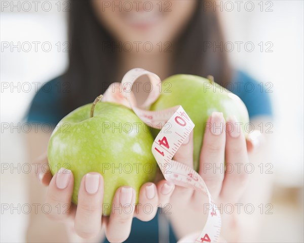 Korean woman holding apples and tape measure