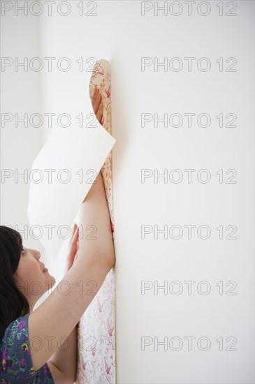 Korean woman putting wall paper on wall