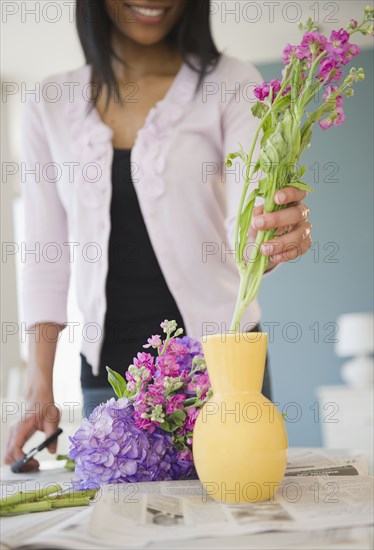 African American woman arranging flowers in base