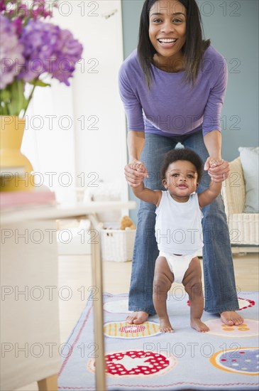 African American mother helping baby boy learn to walk