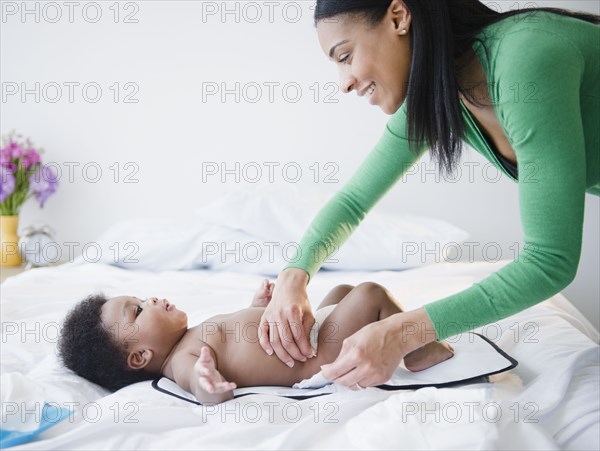 African American mother changing son's diaper